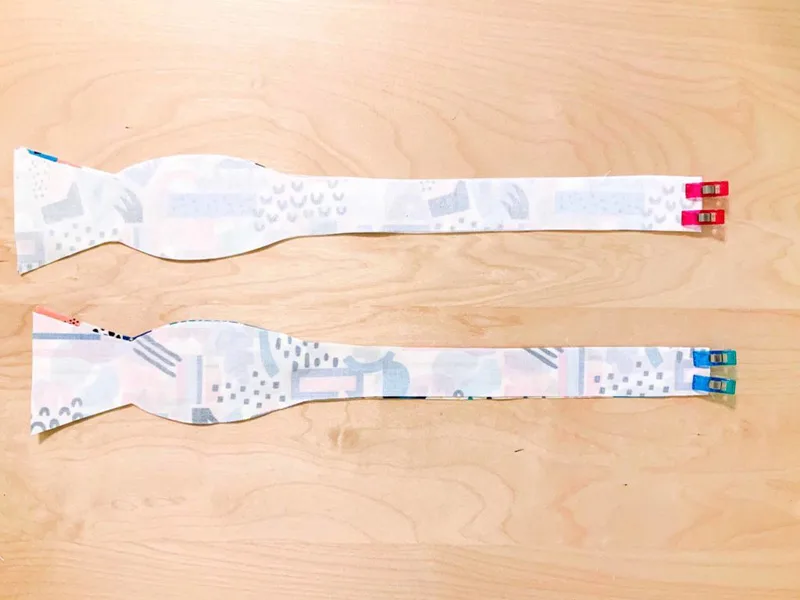 Four bow tie pieces are clipped together design sides facing on a wooden surface.