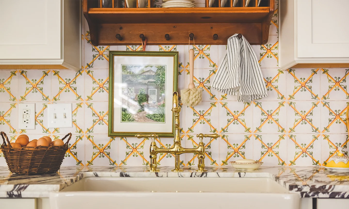 Kitchen with yellow tile wallpaper behind a farmhouse sink.