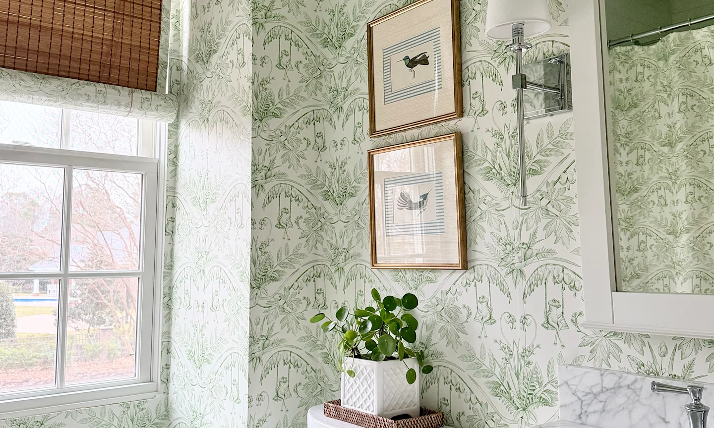 Bathroom with green and cream frog toile wallpaper and a matching shower curtain.