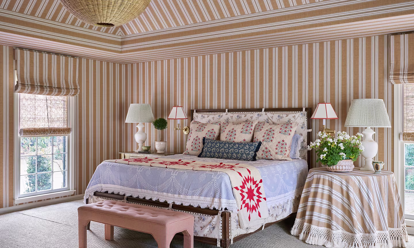 Bedroom wither striped walls and floral block print bedding.