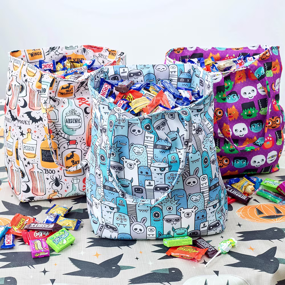 Three bags with halloween prints filled with candy.