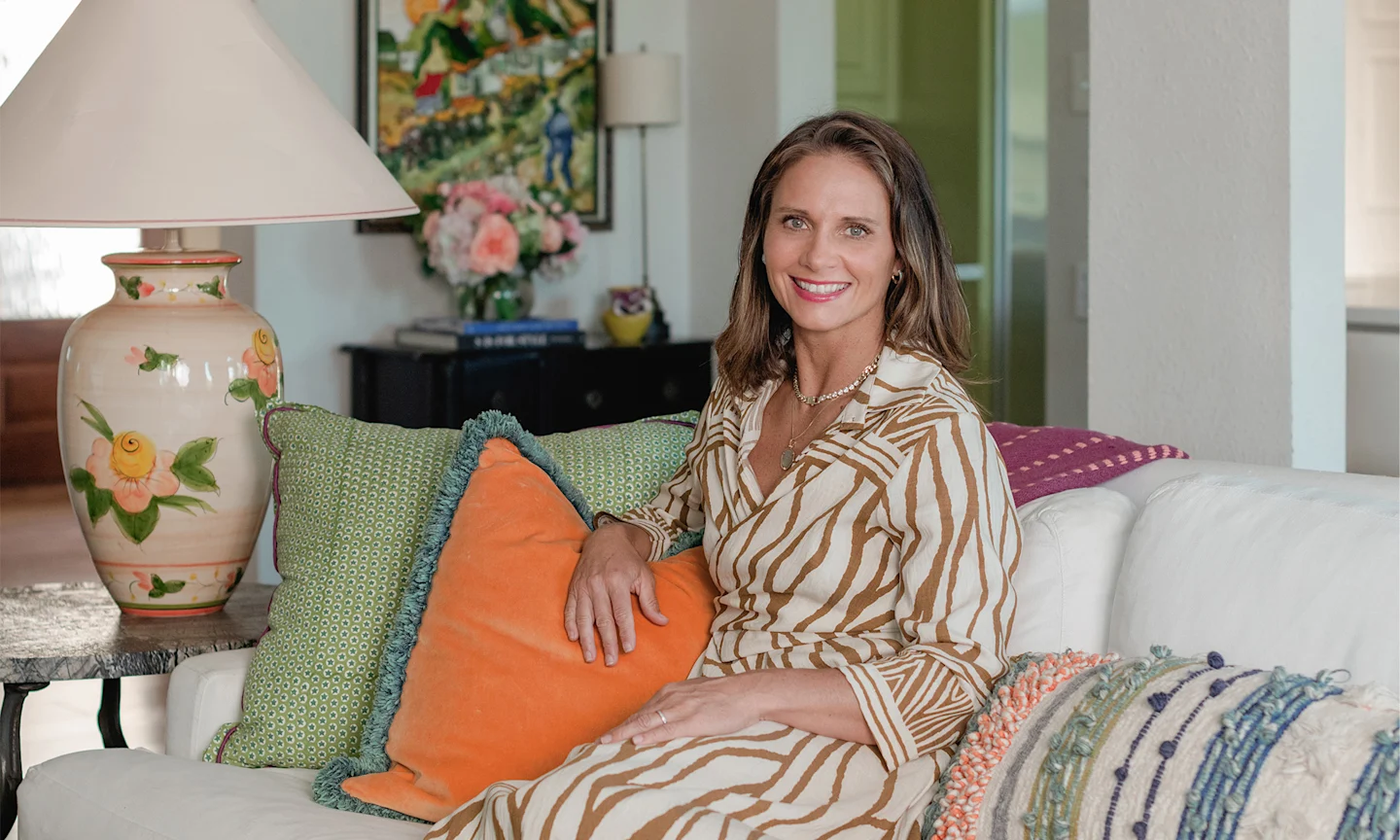 Kim Armstrong sitting on a couch with green and orange pillows.