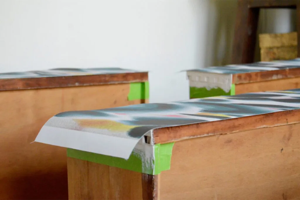 A close up of the dresser drawers facing up with measured wallpaper on top of them.