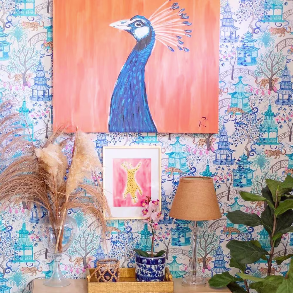 Wall with chinoiserie wallpaper and colorful wall art.