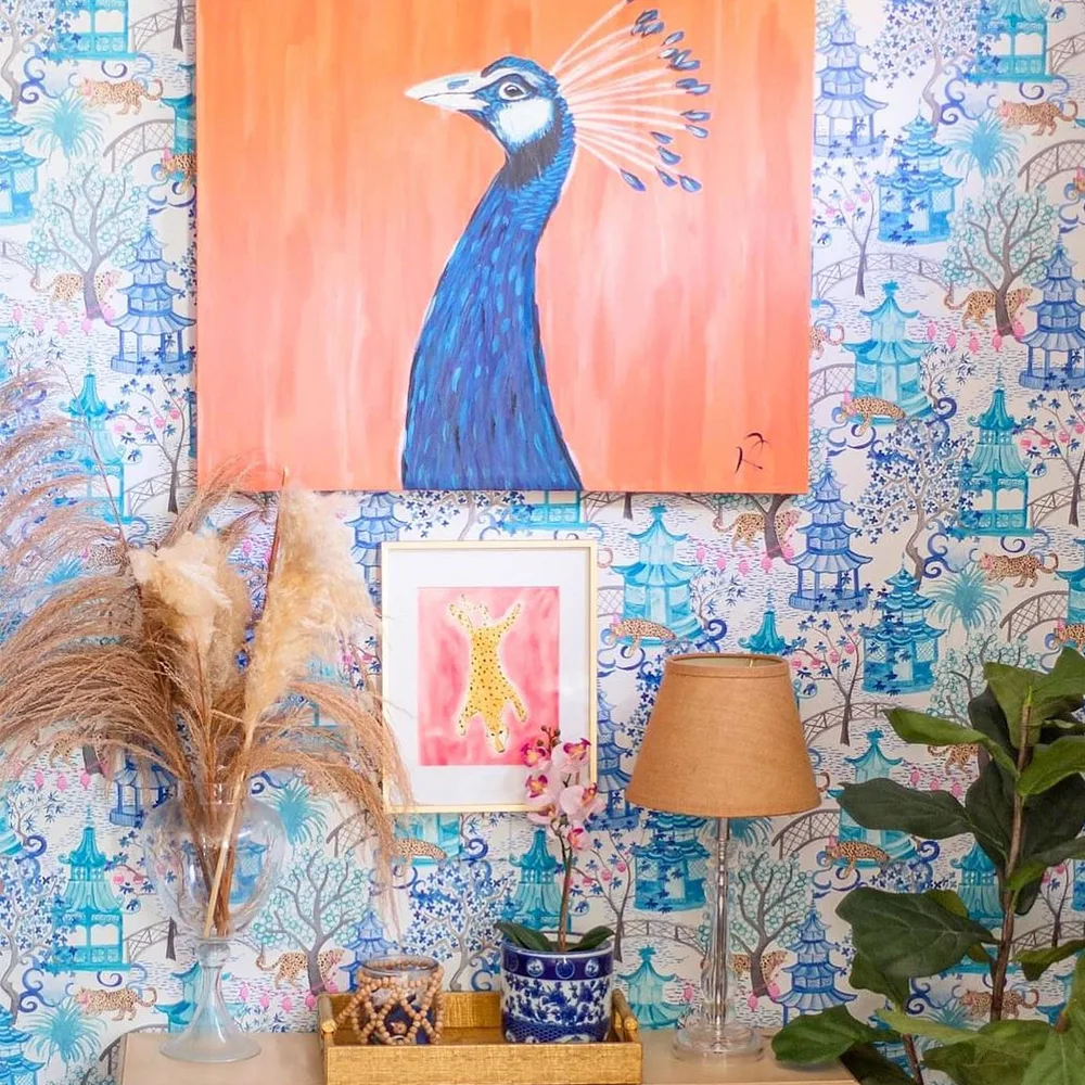 Wall with chinoiserie wallpaper and colorful wall art.