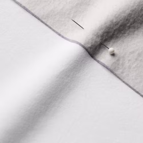 A close-up photo of white fabric with a pin running through it