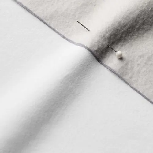 A close-up photo of white fabric with a pin running through it