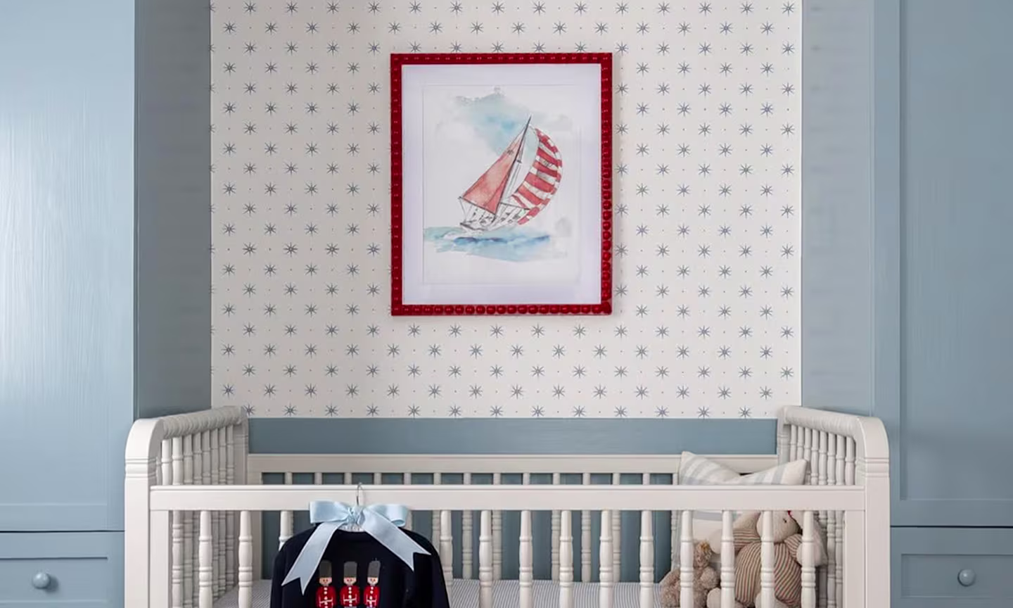 Nursery with star wallpaper and a art print with a sailboat.