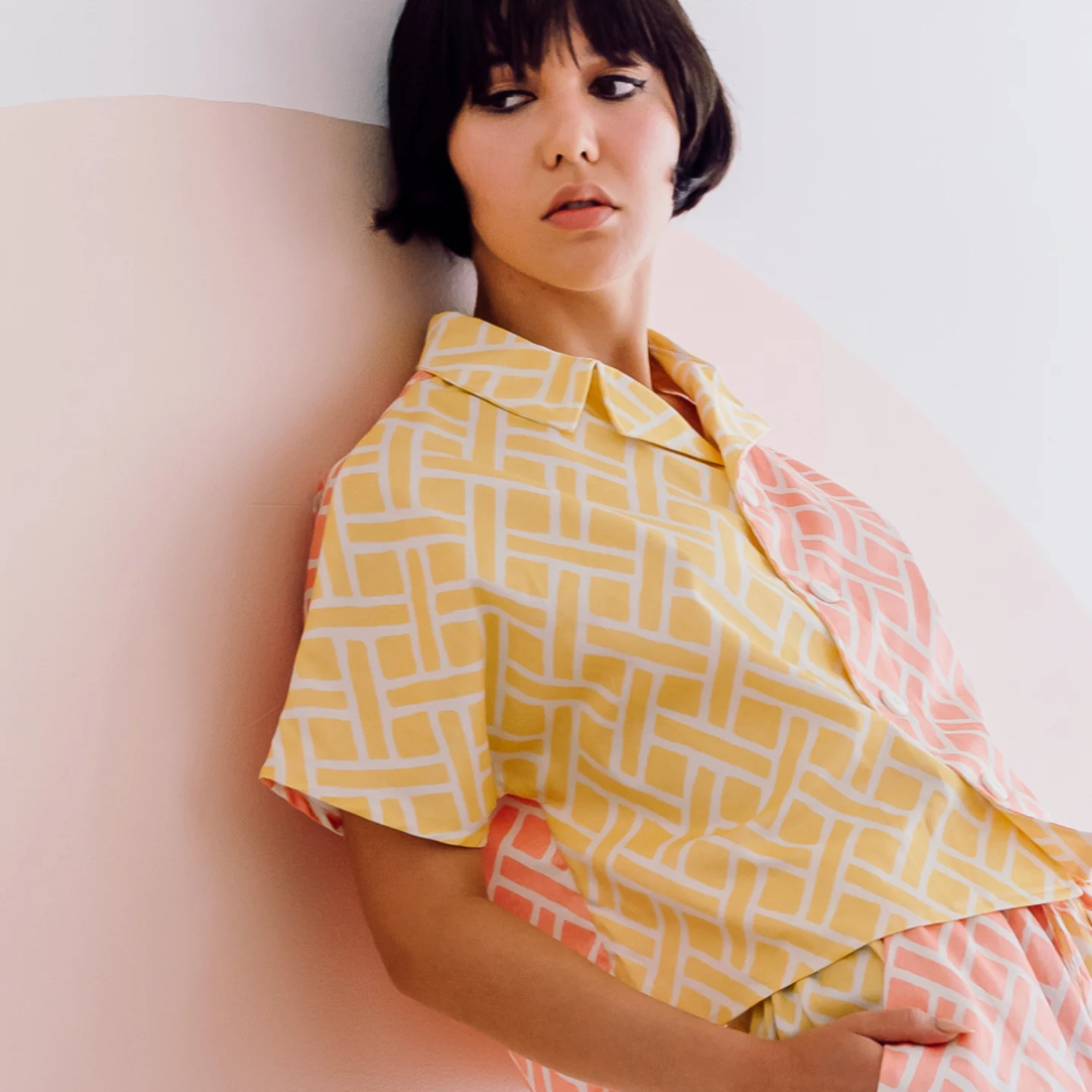 Woman leaning against wall wearing a custom pink and yellow shirt