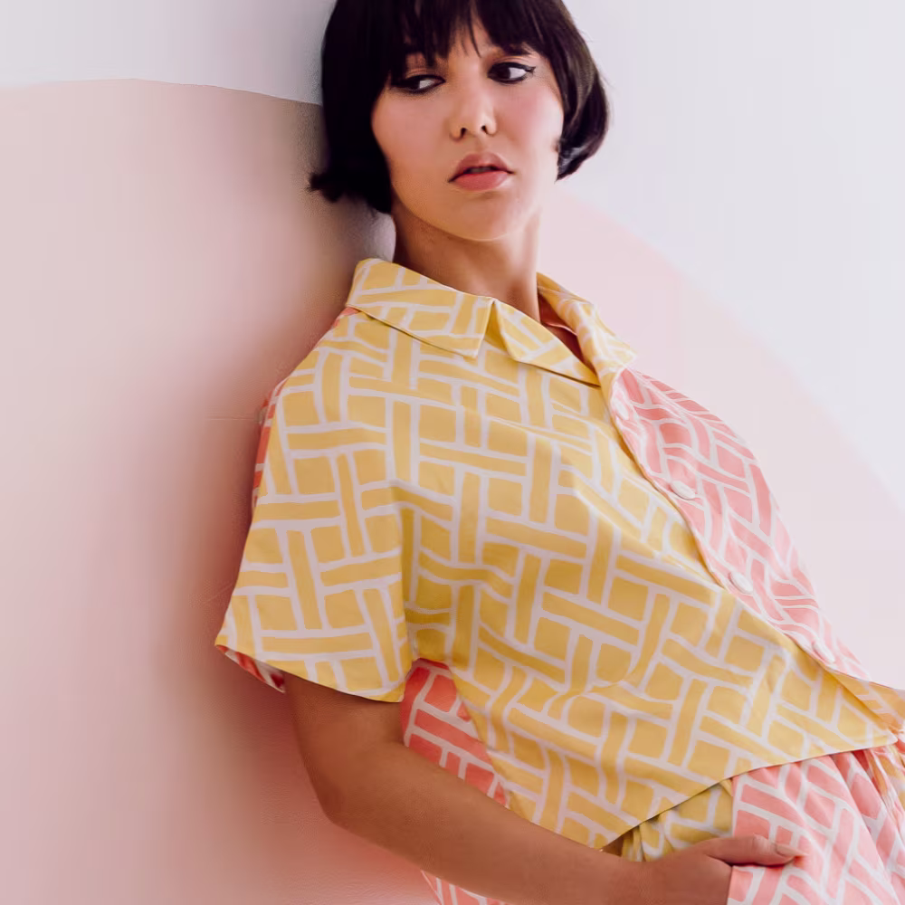Woman leaning against wall wearing a custom pink and yellow shirt