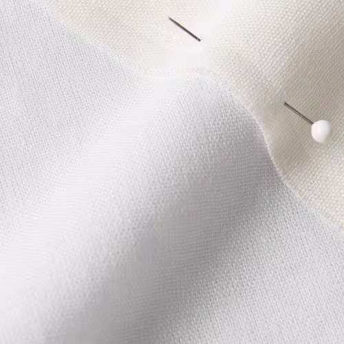 A close-up photo of white fabric with a pin running through it