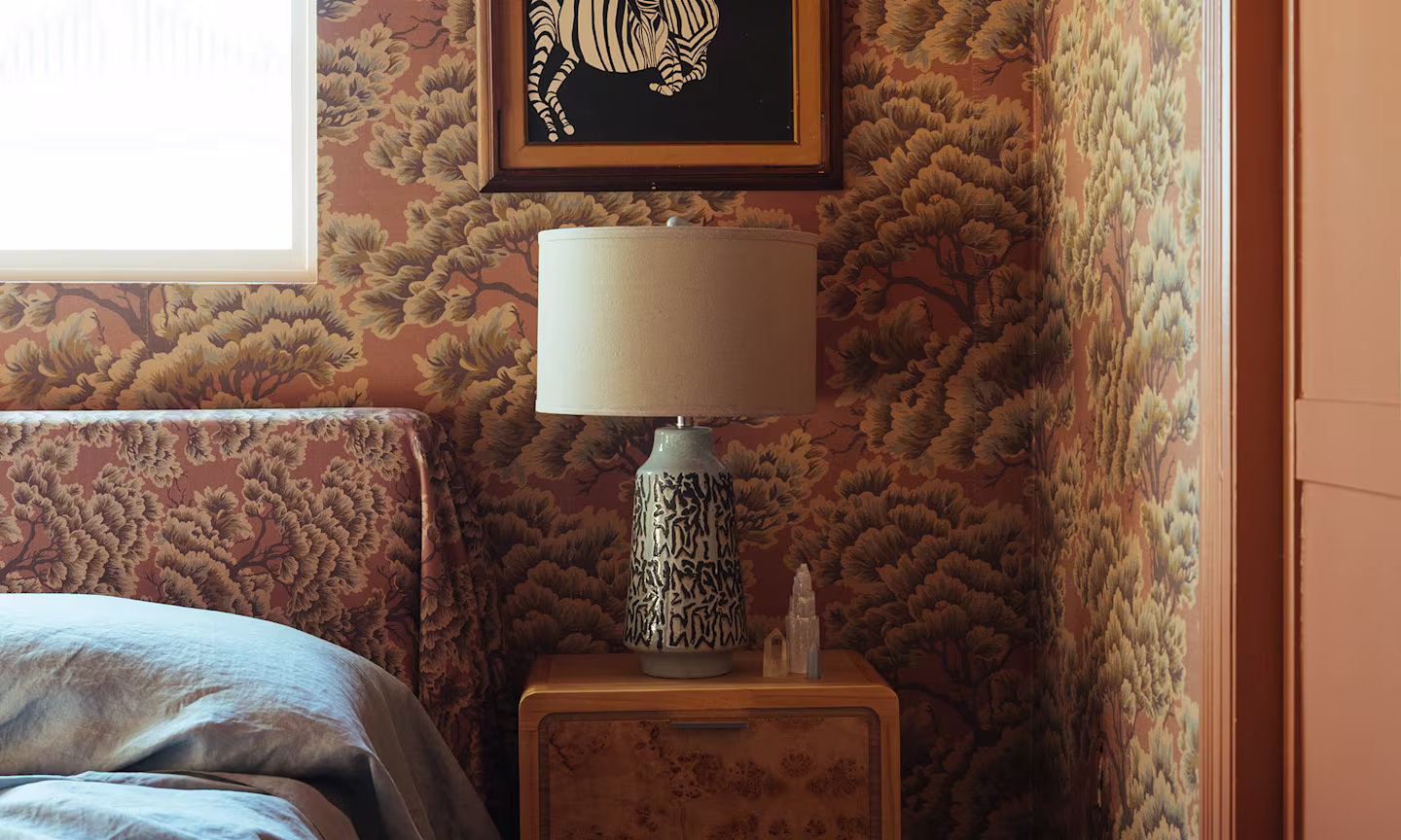Bedroom with mauve tree wallpaper and headboard.