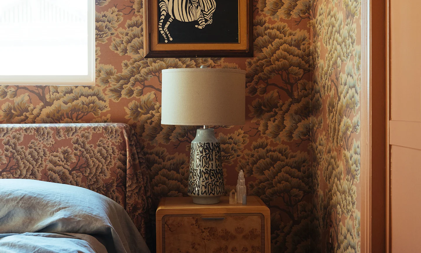Bedroom with mauve tree wallpaper and headboard.