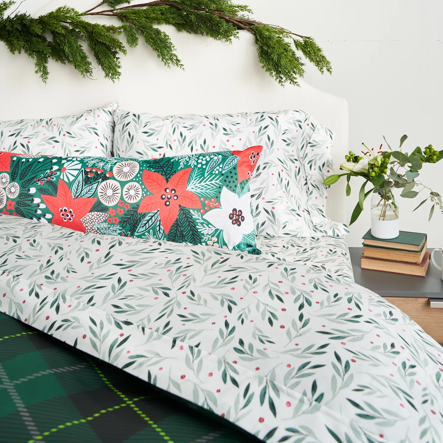 A bed with green and white watercolor christmas sheets