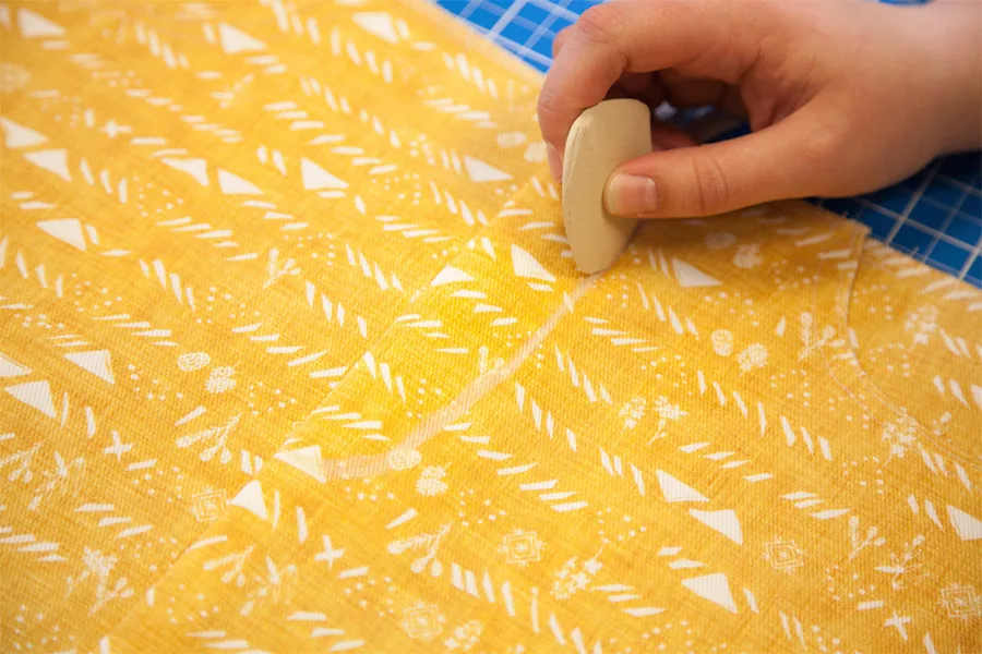 With the fabric turned design side up, MaryAshlynn draws a J along the fly extension with fabric chalk.