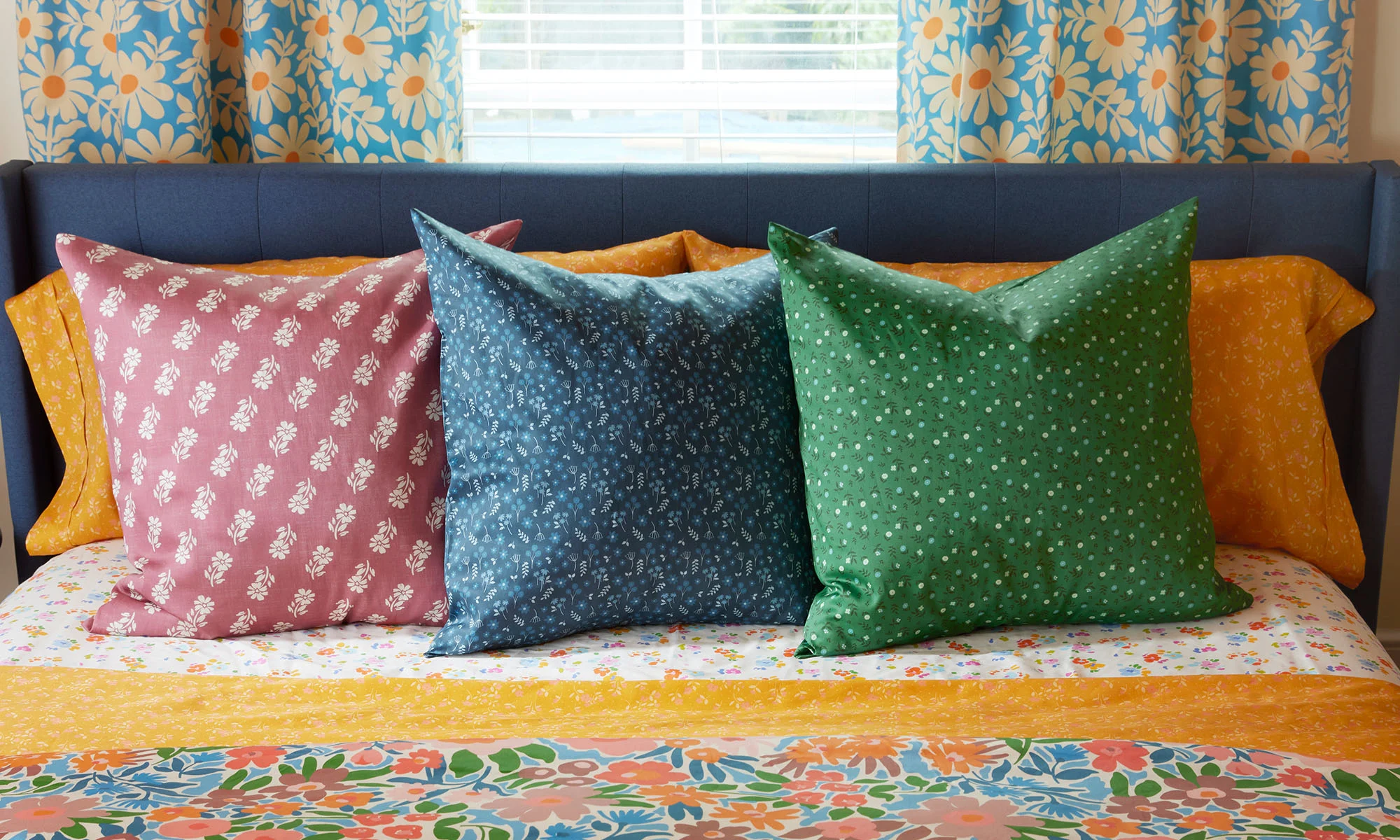 Bed with jewel tone floral printed throw pillows, bedding and curtains.