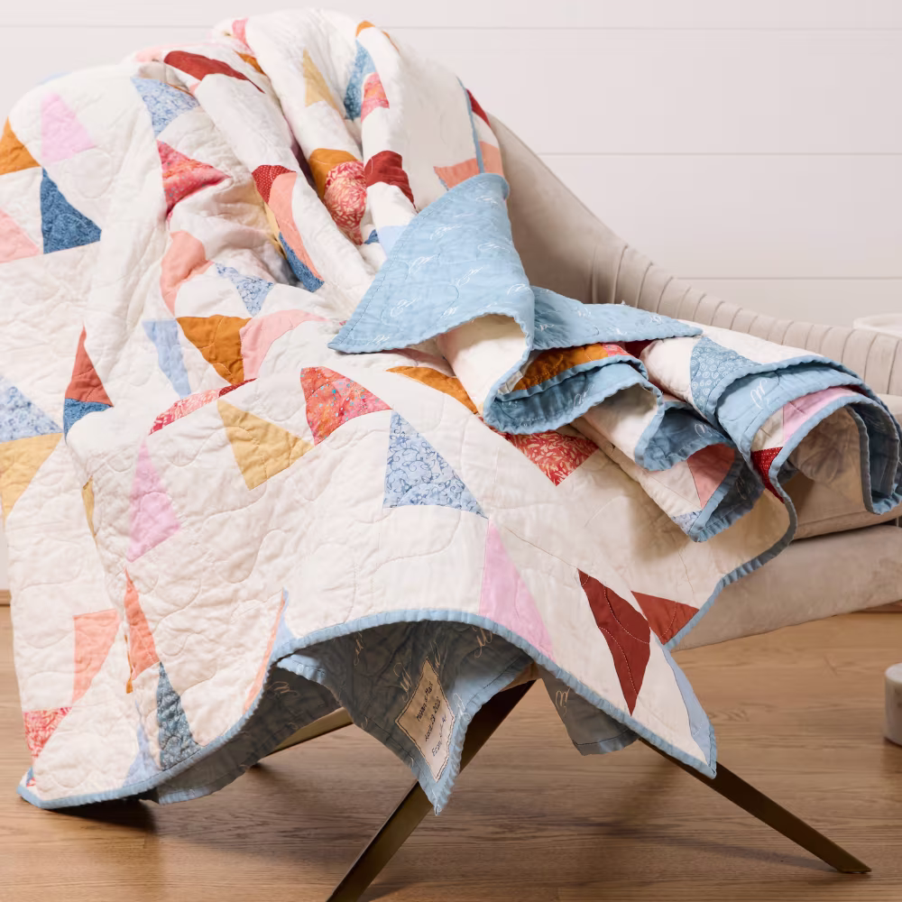 Blue and white cotton sateen quilt laying across a gray chair