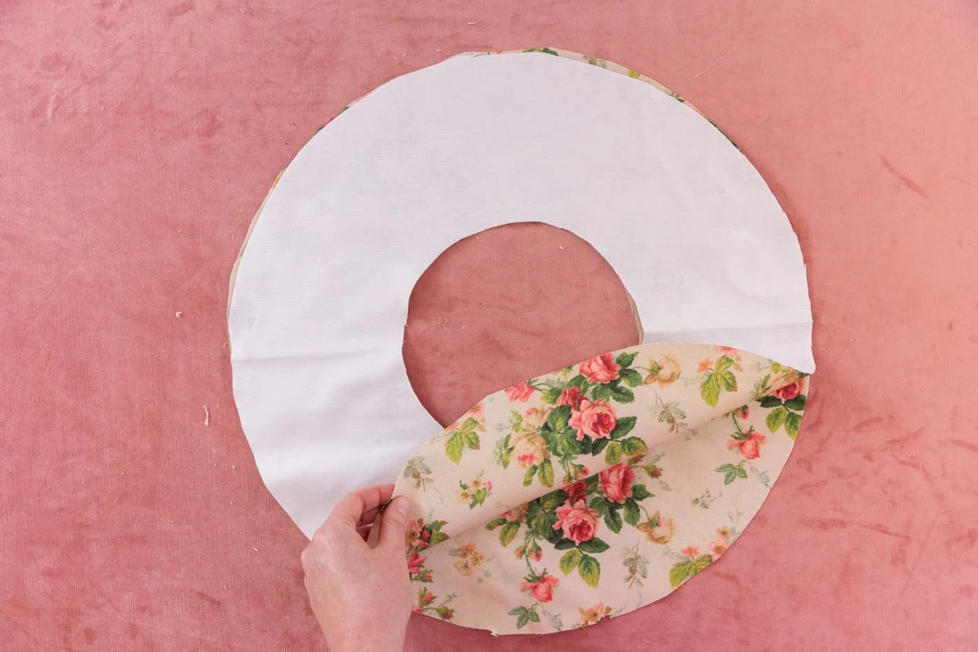 With the two fabrics unfolded in a donut shape, Keiko lifts up one of the pieces of fabric to show the design side of both pieces. The wrong side is white and facing up.