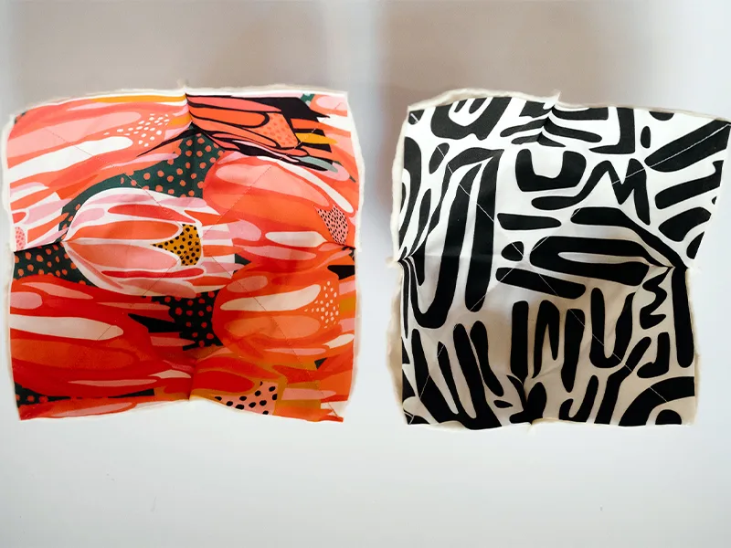 Each side of the bowl cozy has had fabric and batting sewn together complete with darts, resulting in a concave shape. The fabric to the left features bright flowers in pinks, reds, yellows and white. The fabric to the right features black geometric lines