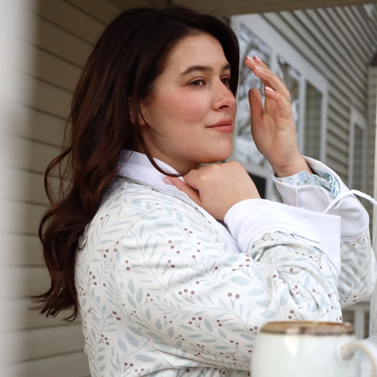 a woman standing on a porch wearing a cozy fleece robe.
