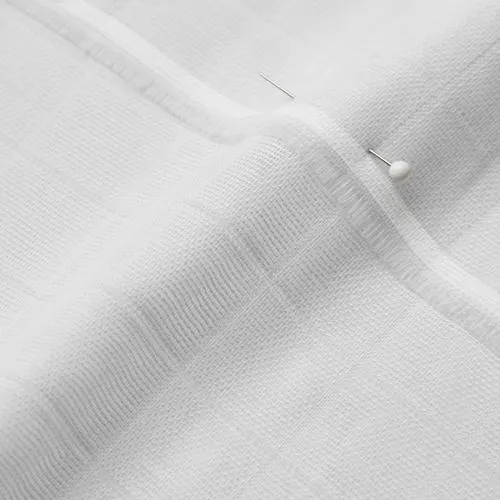 A close-up photo of white fabric with a pin running through it