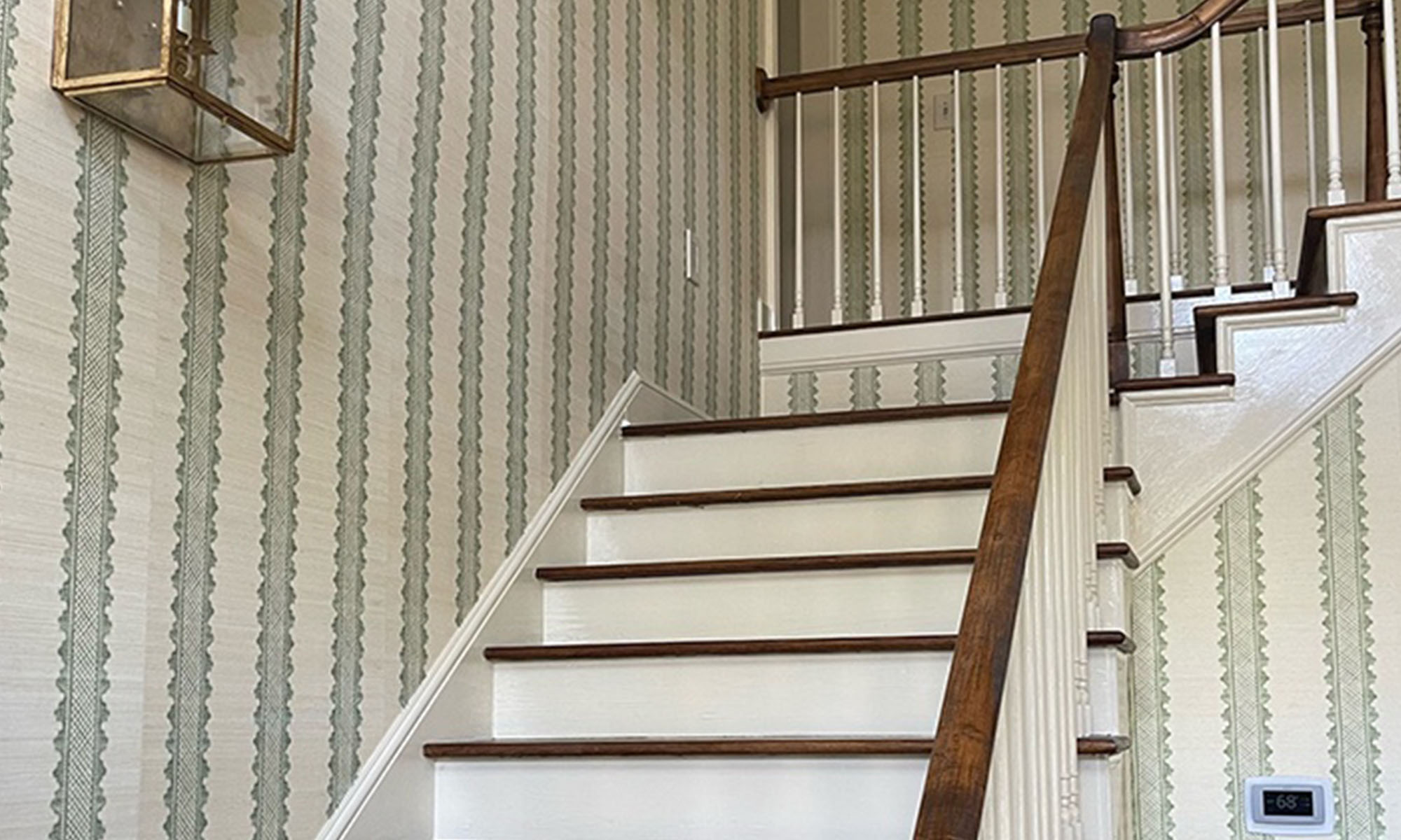A staircase wallpapered with traditional styled green stripes.