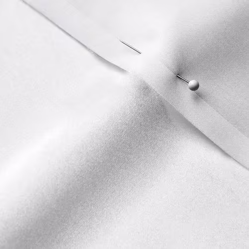 A close-up photo of white fabric with a pin running through it