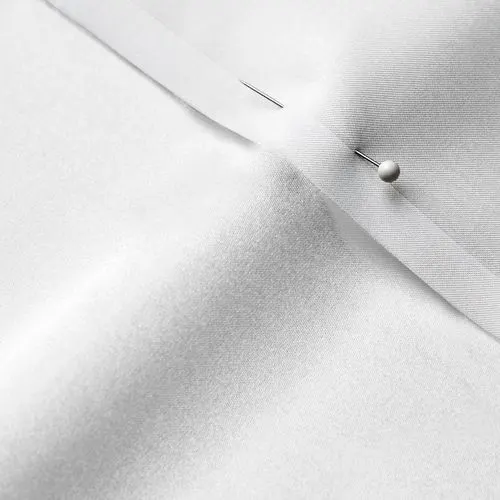A close-up photo of white fabric with a pin running through it