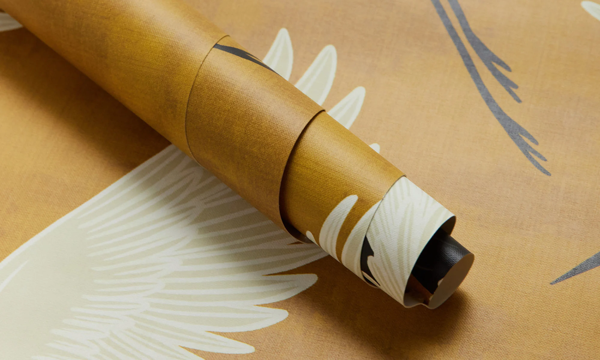 A closeup of Spoonflower's peel and stick wallpaper featuring a gold and ivory crane print.