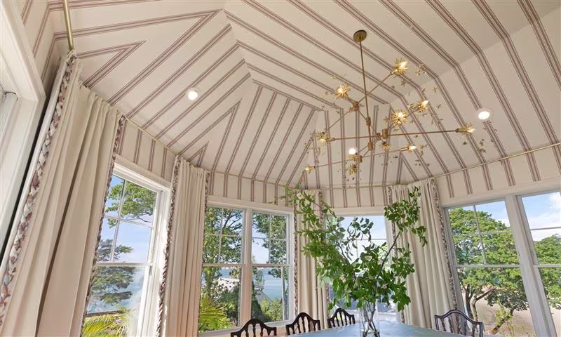 Dining room covered with striped wallpaper on walls and ceiling.