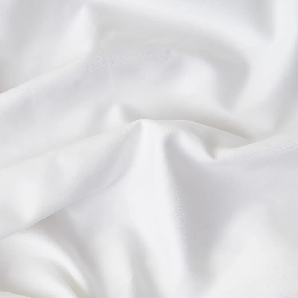 A close-up of white fabric with soft folds and a smooth, slightly lustrous surface.