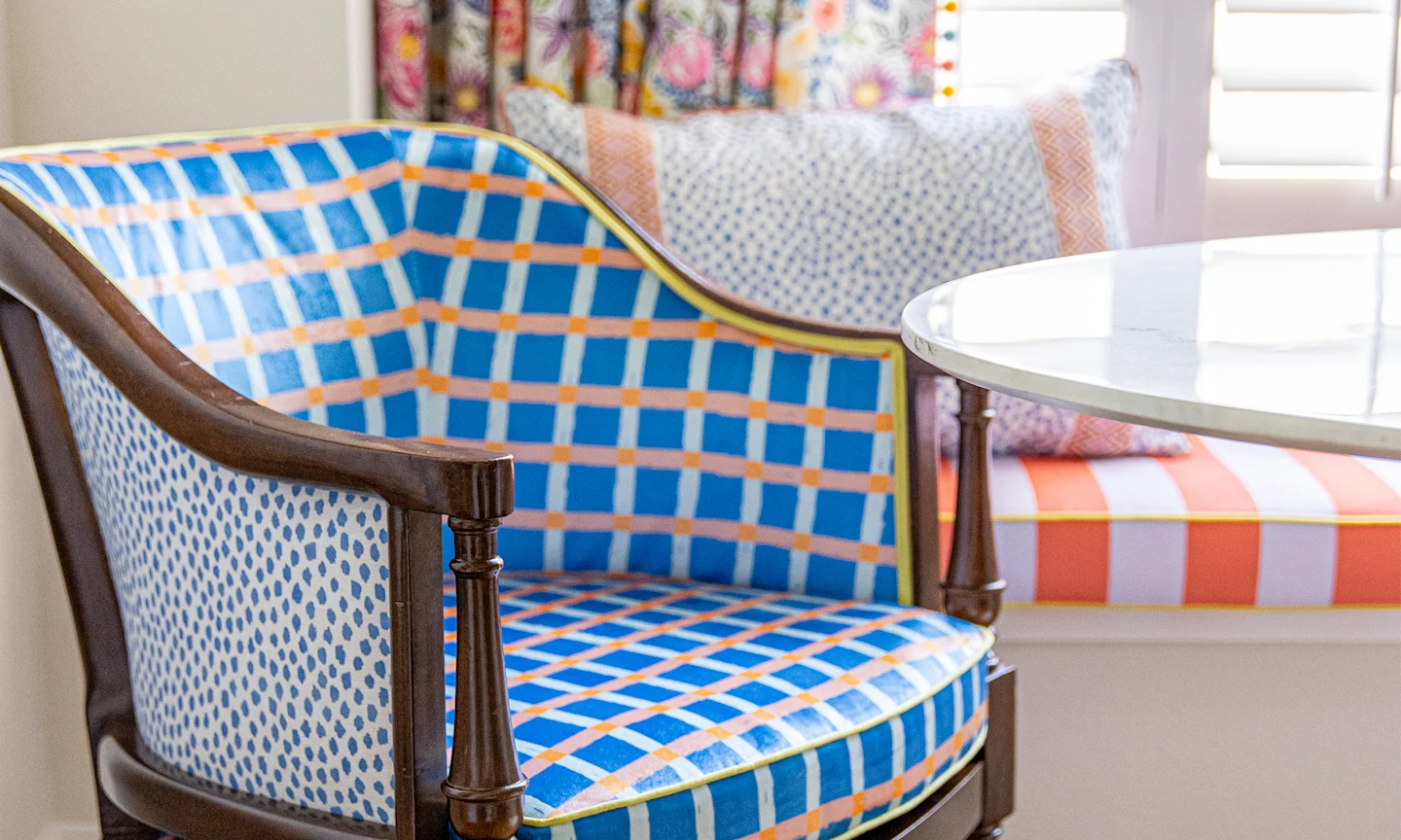 A dining chair with blue plaid fabric on the inside and blue speckle fabric on the outside.