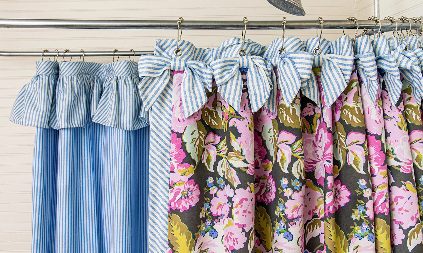 Custom shower curtain with a purple chintz floral fabric on the outside and a blue pinstripe on that inside and as bow accents.