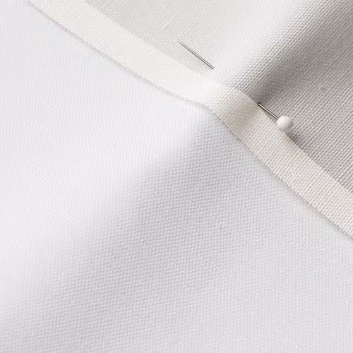 A close-up photo of white fabric with a pin running through it