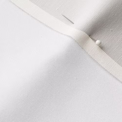 A close-up photo of white fabric with a pin running through it