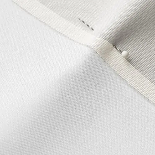 A close-up photo of white fabric with a pin running through it