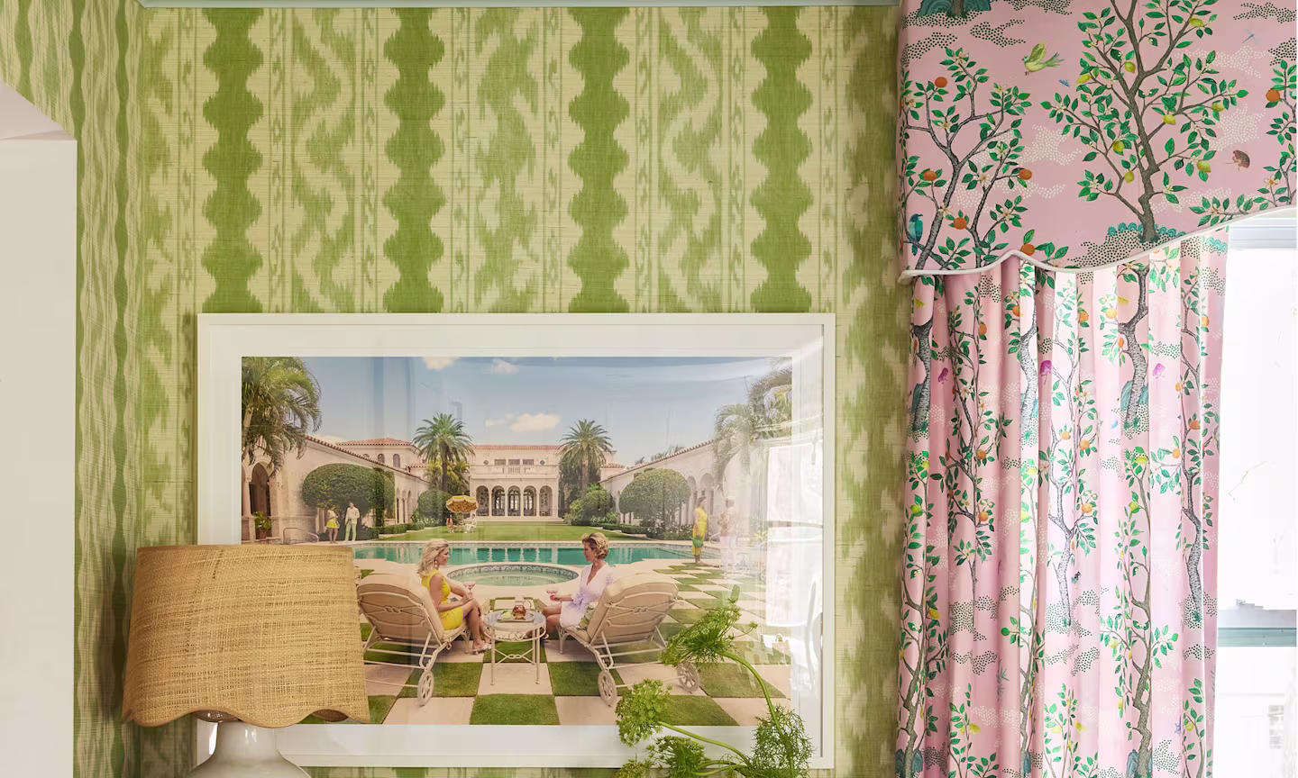 Wall with green wallpaper and pink curtains around a window.