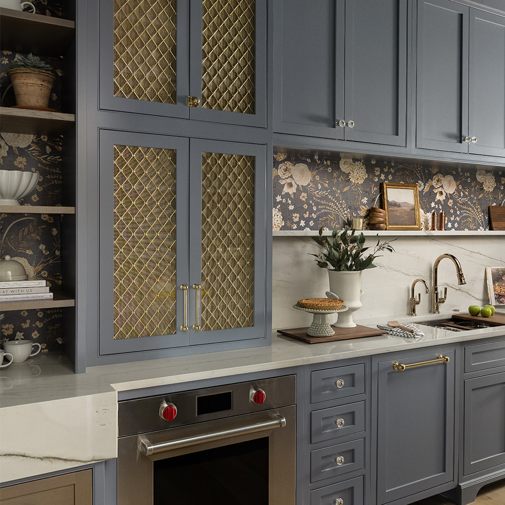 Kitchen with floral wallpaper and blue cupboards.