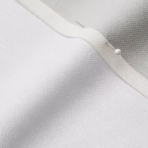 A close-up photo of white fabric with a pin running through it