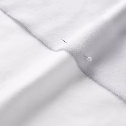 A close-up photo of white fabric with a pin running through it