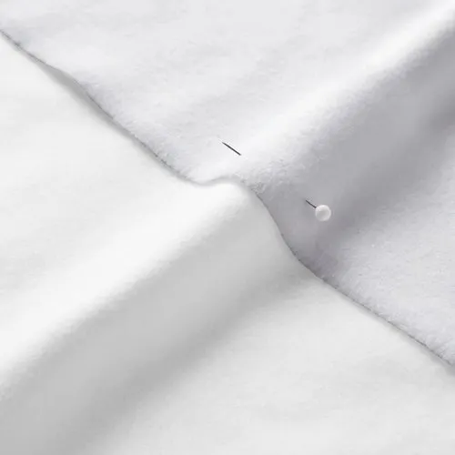 A close-up photo of white fabric with a pin running through it