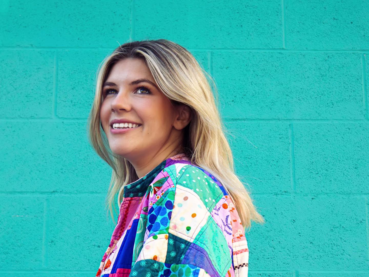 A headshot of Jenna Hall in a handmade quilted coat