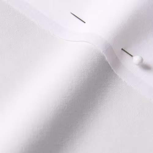 A close-up photo of white fabric with a pin running through it