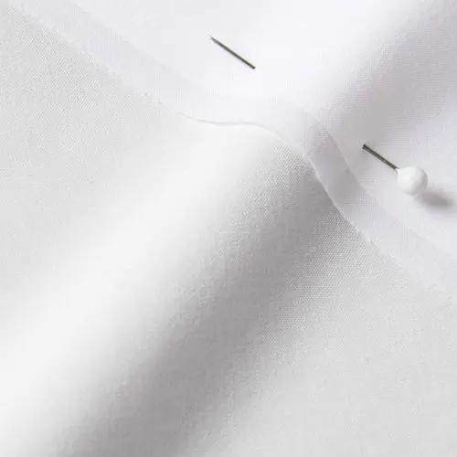 A close-up photo of white fabric with a pin running through it
