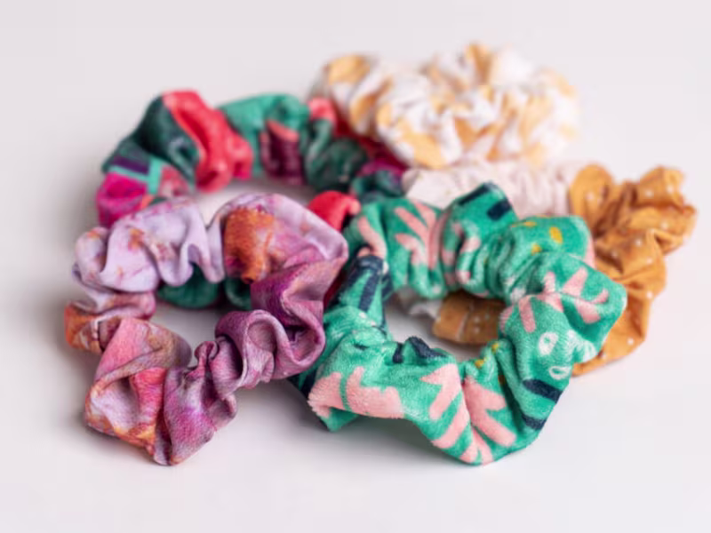 five scrunchies in various colors lay on a white background.