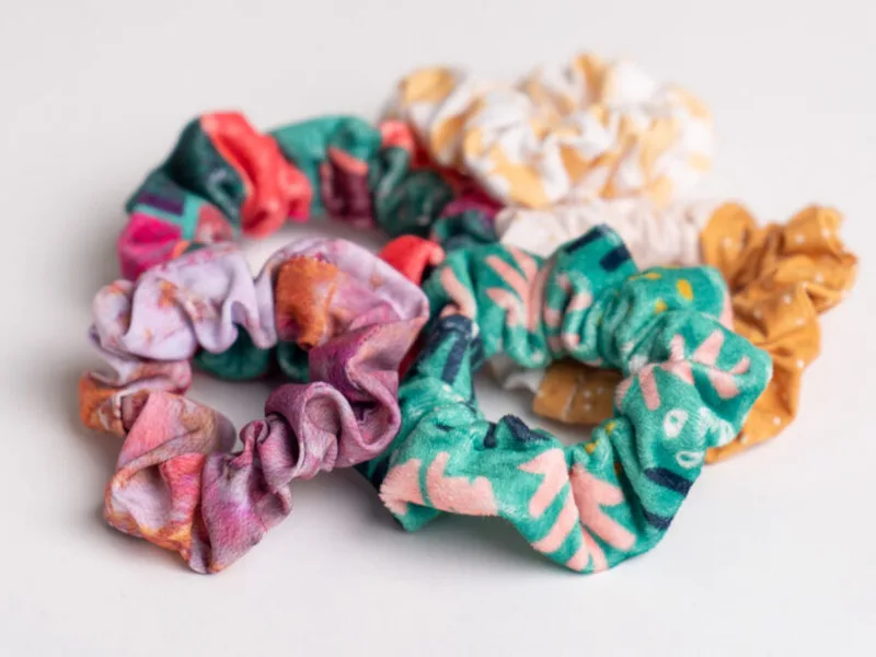 five scrunchies in various colors lay on a white background.