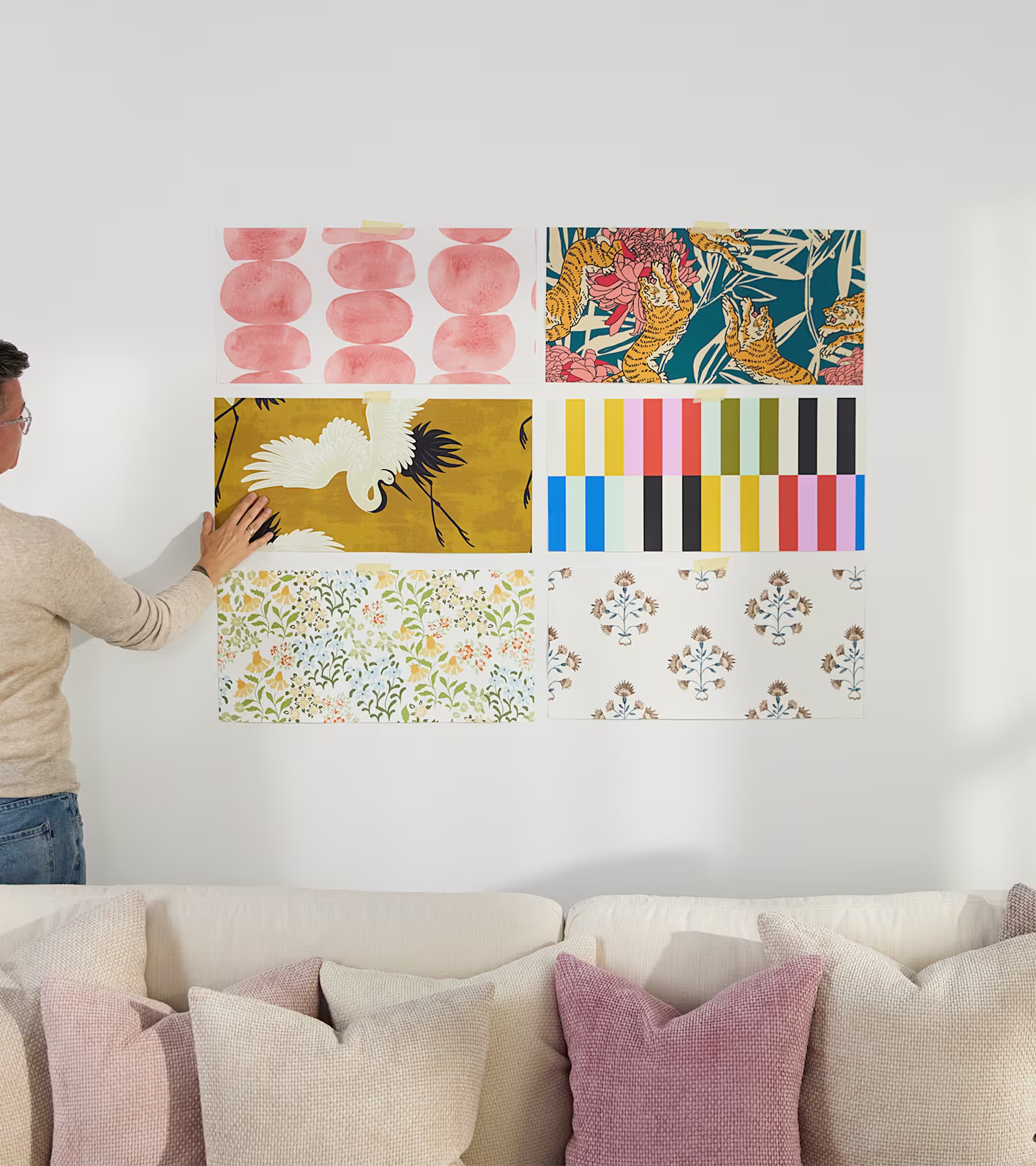 Person assessing wallpaper samples on a wall