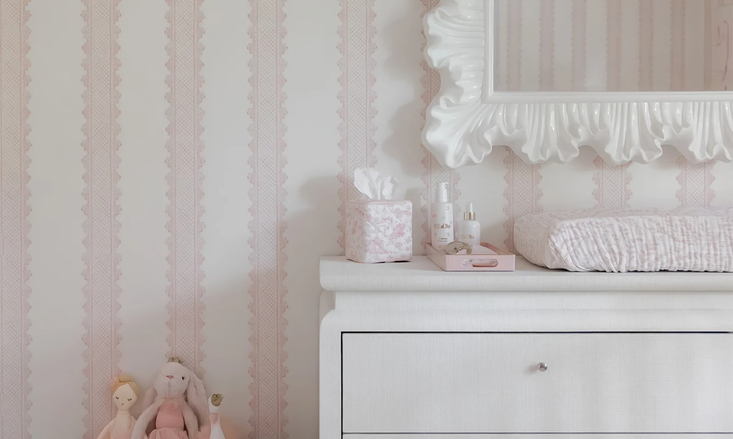Nursery with pink stripe wallpaper.