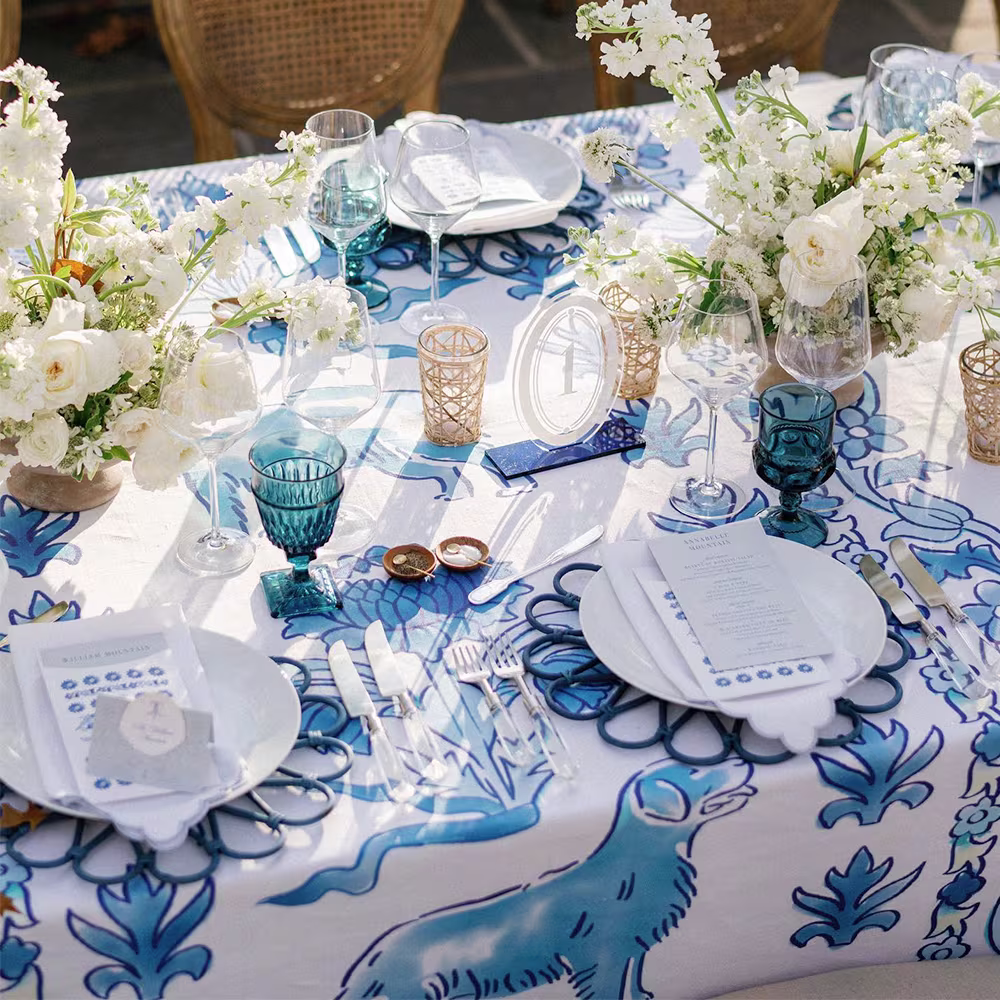 Wedding reception table with a blue dog and floral tablecloth, florals and table settings.