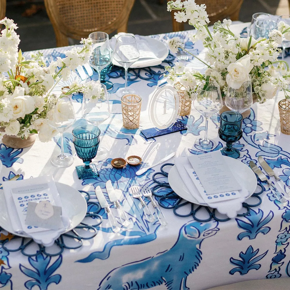 Wedding reception table with a blue dog and floral tablecloth, florals and table settings.